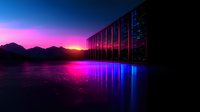 Modern glass building reflecting vibrant sunset over mountain landscape with neon purple and blue light reflections on water surface creating futuristic cyberpunk atmosphere.