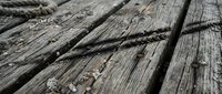 Weathered wooden dock planks with rope detail showing natural aging and texture for rustic maritime and nautical design projects.
