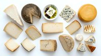 Assorted gourmet cheese varieties including aged cheddar, blue cheese, brie, gouda and artisanal selections arranged on white background for culinary presentations.