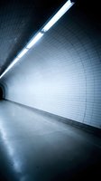 Modern underground tunnel with white tiled walls and fluorescent lighting creating atmospheric perspective for urban transportation concepts.