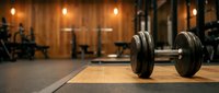 Dumbbell on wooden platform in modern gym with warm lighting, exercise equipment and blurred background for fitness training concepts.