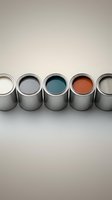 Row of open paint cans with colorful interior paints including white, gray, teal, orange and beige for home renovation and decorating projects.