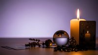 Relaxing spa composition with burning candles, crystal ball and lavender on wooden surface against purple gradient background for wellness meditation.