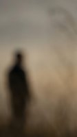 Blurred silhouette of person standing in foggy atmospheric conditions with warm beige and gray tones creating mysterious mood for creative projects.