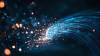 Glowing blue fiber optic strands with orange light particles creating dynamic motion effect against dark background, modern technology concept.