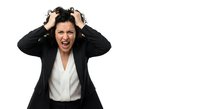 Frustrated businesswoman pulling hair screaming in stress isolated on white background expressing workplace burnout and overwhelming pressure.