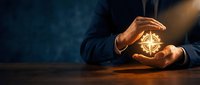 Businessman holding glowing geometric shape in cupped hands against dark background, representing innovation, technology, and business solutions for corporate and entrepreneurial concepts.