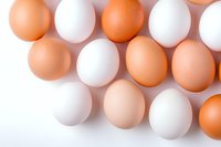 Fresh brown and white chicken eggs arranged on white background, top view composition showing natural color variation and organic texture. Food concept.