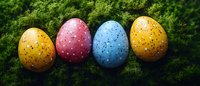 Colorful speckled Easter eggs in yellow, pink, and blue arranged in row on green moss background, festive spring holiday decoration for seasonal designs.
