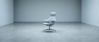 Modern gray office chair with headrest in empty minimalist concrete room, suitable for corporate, interior design, and furniture catalog use.