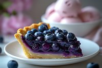Fresh blueberry pie slice on white plate with glossy purple filling and golden flaky crust, garnished with fresh berries, soft focus background with pink accents.