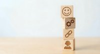Wooden blocks with business icons stacked vertically showing customer service workflow from happy face to employee on neutral background.