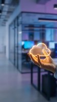 Hand holding glowing cloud symbol in modern office representing cloud computing technology and digital transformation for business solutions.