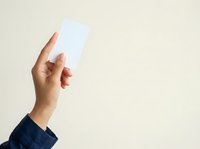 Hand holding blank white card against neutral background, suitable for mockups, business presentations, and promotional designs.