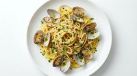 Spaghetti alle vongole with fresh clams and garlic on white plate, overhead view for restaurant menu or food blog content.