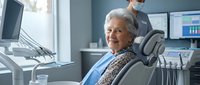 Senior Caucasian woman patient sitting comfortably in modern dental chair during routine checkup with masked dentist working in background at clinic.