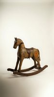 Vintage wooden rocking horse with leather saddle on white background, antique handcrafted toy with rustic charm for nursery decor.
