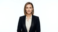 Professional businesswoman in black blazer and white shirt smiling confidently on isolated white background for corporate design and marketing materials.