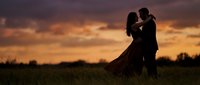 Romantic couple silhouette embracing in field during golden sunset sky. Love, relationship, engagement concept for wedding invitations and romance designs.