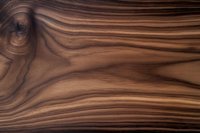 Natural brown wood grain texture with swirling patterns and dark knots creating an organic flowing design on smooth polished surface. Suitable for luxury furniture.