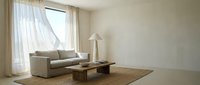 Minimalist living room with neutral beige sofa, wooden table, floor lamp, and sheer curtains by window. Spacious interior design for home decor and furniture styling projects.