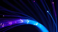 Abstract blue and purple fiber optic cables with glowing light points creating dynamic flowing lines against dark background for technology concepts.