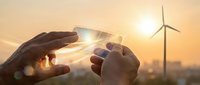 Hands protecting wind turbine at sunset symbolizing renewable energy conservation and sustainable future with golden sky backdrop for environmental concepts.