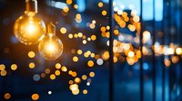 Glowing vintage light bulbs hanging against blurred bokeh background creating warm atmospheric lighting effect for festive or cozy interior design.