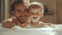 Joyful father and toddler son share laughter during bath time, surrounded by bubbles in warm sunlit bathroom. Candid family moment captures pure happiness.