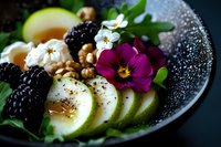 Fresh green apple slices with blackberries, walnuts and edible flowers on dark plate. Healthy organic food styling with natural ingredients and garnish.