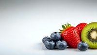 Fresh mixed berries and kiwi fruit arrangement on white background for healthy eating and nutrition concepts in food photography and culinary design.