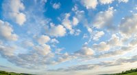 Dramatic blue sky with fluffy white clouds over green landscape horizon. Perfect for nature backgrounds, weather concepts, and outdoor advertising campaigns.