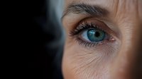 Close-up of mature woman's blue eye with natural wrinkles and long eyelashes showing aging process and skincare concepts for beauty industry.