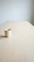 Minimalist white ceramic cup on light wooden table with neutral background, suitable for product placement, lifestyle, and interior design projects.
