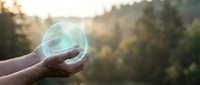 Hands holding glowing transparent sphere with green earth continents at sunset, symbolizing environmental protection and global sustainability concepts.