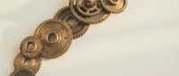Vintage brass mechanical gears and cogs arranged on neutral background for steampunk industrial design projects and engineering concepts.