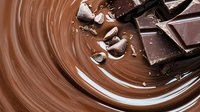 Melted milk chocolate swirl with broken dark chocolate pieces and silver candy foil creating dynamic composition for confectionery and dessert designs.