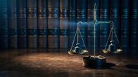 Scales of justice on wooden desk with law books in background, legal concept for courtroom, attorney office, judicial system and legal services.