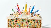 Colorful birthday cake with lit candles and sprinkles, perfect for celebrations, party invitations, greeting cards, and festive event marketing materials.