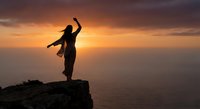 Woman hiker celebrating success on mountain cliff edge at golden sunset over ocean. Achievement, adventure, freedom and triumph concept for motivation.