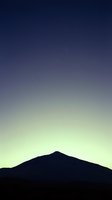 Mountain silhouette against twilight sky with stars emerging at dusk. Serene landscape suitable for backgrounds, nature themes, and peaceful atmospheric designs.