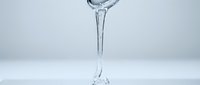 Clear water pouring into glass against white background, suitable for beverage, hydration, wellness and refreshment concepts.