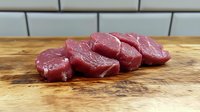 Fresh raw beef steaks on wooden cutting board in modern kitchen ready for cooking and grilling preparation.