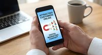 Businessman holding smartphone displaying customer attraction marketing strategy with magnet icon and people graphics on screen at office desk.