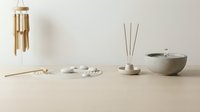 Minimalist zen spa arrangement with bamboo chimes, incense sticks, ceramic bowls and natural elements on wooden surface for wellness and meditation.