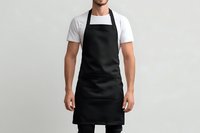 Young Caucasian male chef or barista wearing black apron and white t-shirt against neutral gray background, ready for restaurant or cafe service.