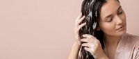 Young woman with closed eyes enjoying music through wireless headphones against soft pink background for relaxation and audio entertainment concepts.