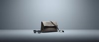 Stylish brown leather messenger bag with sunglasses and accessories arranged on neutral surface for fashion and lifestyle design projects.