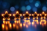 Glowing star-shaped lights creating warm golden reflections against dark blue bokeh background, festive holiday decoration for Christmas and celebrations.