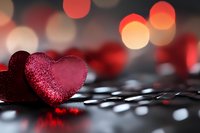 Red glittery heart decoration on reflective surface with warm bokeh lights creating romantic Valentine's Day atmosphere for love celebrations.